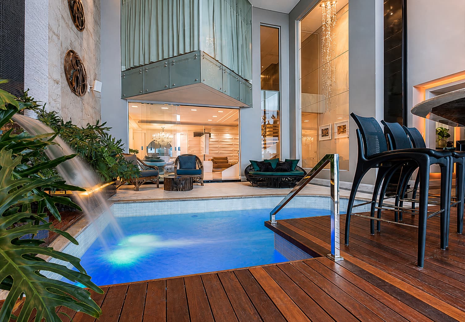 Piscina interna com deck de madeira e iluminação noturna